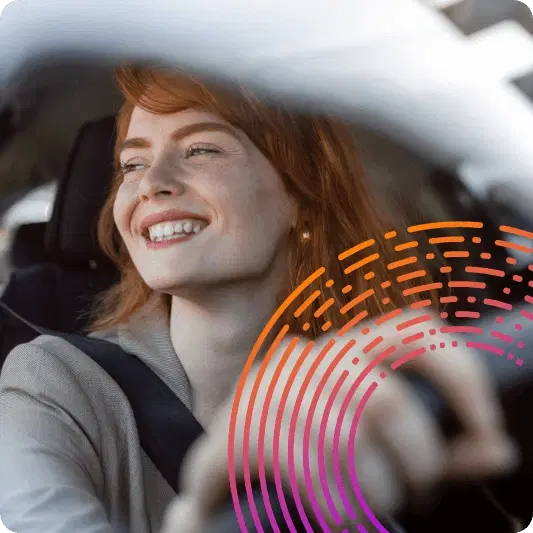 Red headed lady smiling out of a car window